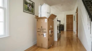 A rolled open coil mattress in a compact delivery box resting in a hallway after online ordering.